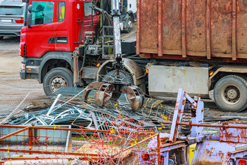 A grapple truck loads scrap industrial metal for recycling.