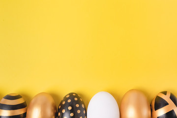Flat Lay of Golden Easter Eggs on yellow background. Minimal easter concept. Happy Easter card with...