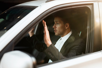 young businessman looks astonished with his hands up near the wheel being stopeed by police while driving his car , safety driving concept