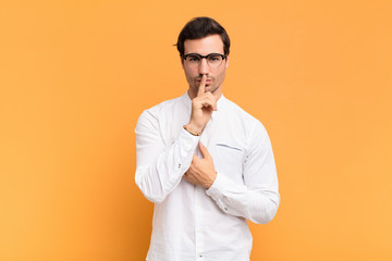  looking serious and cross with finger pressed to lips demanding silence or quiet, keeping a secret