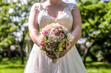 Wedding bouquet of flowers held by bride closeup. Pink and yellow roses flowers