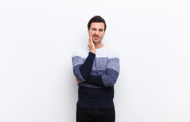 young handsome man holding cheek and suffering painful toothache, feeling ill, miserable and...
