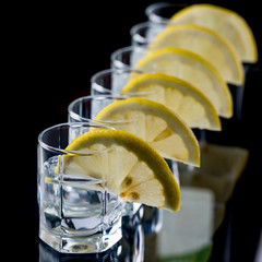 The bartender pours a strong liquor into small glasses, such as tequila alcoholic drinks or spirits.