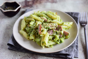Italian pasta with ham and broccoli sauce, cheese and cream on a white plate close-up on a gray background