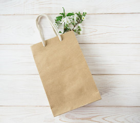 Recycled  brown craft paper bag with handles.Fresh green leaves.White background.Mockup for design.Flat lay.
