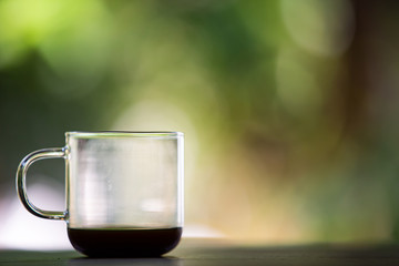 Coffee glasses cup with coffee stains stuck on them, then after drinking it on wooden table in bokeh blurred green garden background, Close up shot, Selective focus
