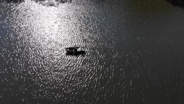 Aerial shot of Brides swim in a red boat. The bright sun is reflected in the lake creating a reflection and flickering glare.