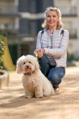 attractive middle-aged blond woman walking with dog in summer city