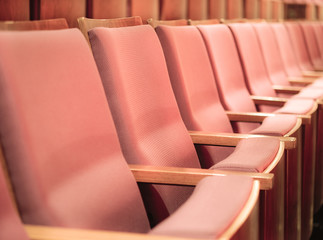 Selective focus of Empty rows of armchairs in hall. Empty pink chairs in conference hall or theater. 