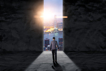 The double exposure image of the businessman standing in front of the door during sunrise overlay with cityscape image. The concept of modern life, business, city life and future.