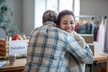 Man in plaid shirt hugging young smiling girl.