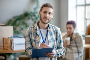 Obraz premium Young handsome man standing with folder and pen in his hands.