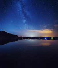 A night on the lake with a bright milky way in the sky and millions of stars glittering in the water