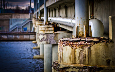 Fototapeta na wymiar Side of a bridge with metal pipes. Cement poles. Bridge structure.