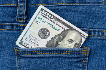 One hundred dollar banknote money in pocket jeans pants background texture. 100 dollar bill close up
