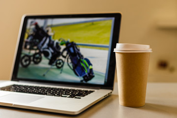 Craft paper coffee cup near laptop, news