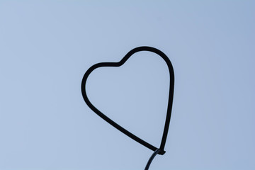 Metal heart shape on background sky