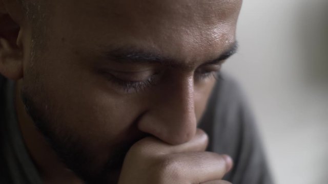 Asian Male Rocking Back And Forth With Hand In Front Of Mouth Looking Down. Close Up, Locked Off