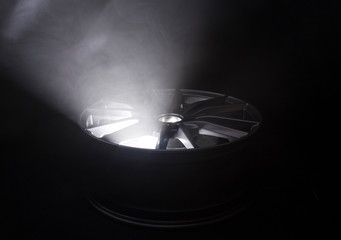 Modern beautiful car alloy wheel in the form of rays that is highlighted by rays of light and...