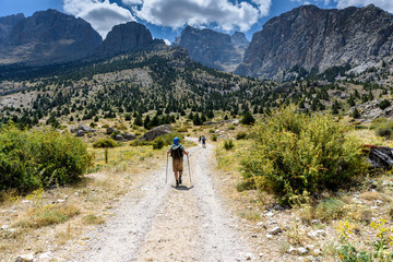 Obraz premium Turkey, Chamard - August 3, 2019: Tourists walk along the road through the mountain landscape in the Turkish national Park aladag in summer day, view from the back