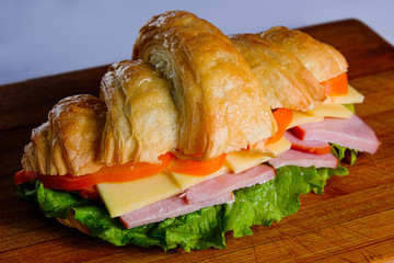 croissant with ham and cheese isolated on a wooden background