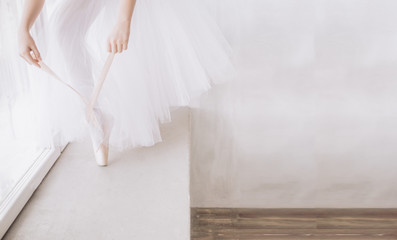 Ballet dancer's feet on studio floor. Teenage dancer puts on ballet pointe shoes. Elegance and balance concept top horizontal view copyspace.