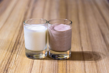 cream and chocolate dessert made of sour cream in glasses on the background of a bamboo table top close-up