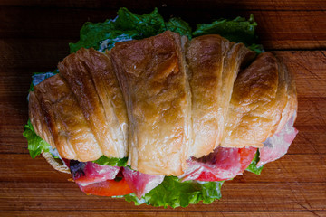 Croissant sandwiche with salmon red fish on a wooden background