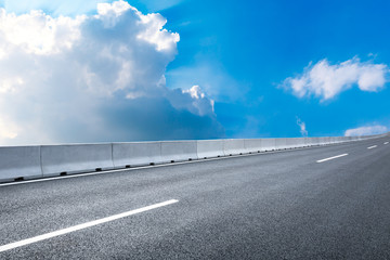 Fototapeta premium Empty asphalt road and blue sky with white clouds in summer