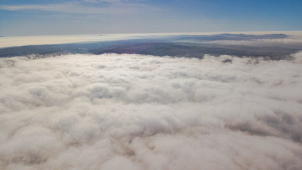 Landscape over the clouds in foggy weather. Hills of buildings in foggy weather. The drone and the top of the fog layer.