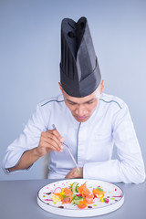 An Asian Executive Chef plating his dish carefully putting his finishing touch to the vibrant dish.