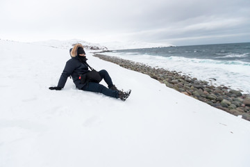 Fototapeta na wymiar man sit down in a white snow coat travel winter mountains ocean sea