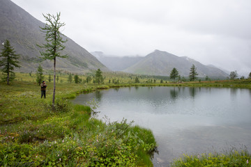 Mountain lake with green grass on the shore. Mountains of the Polar Urals