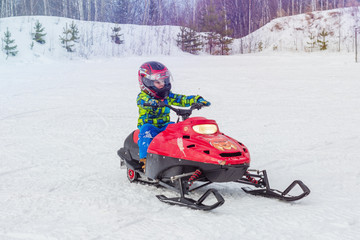 child driving a snowmobile