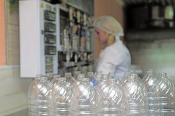 line of production of refined sunflower oil. Girl worker at a factory on a conveyor background with bottles of vegetable oil.