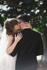 gorgeous young bride and stylish groom are hugging on wedding day outdoors, wedding couple, luxury wedding.