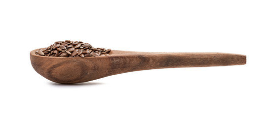 Linseeds or flax seed on a brown wooden spoon seen from the side and isolated on white background