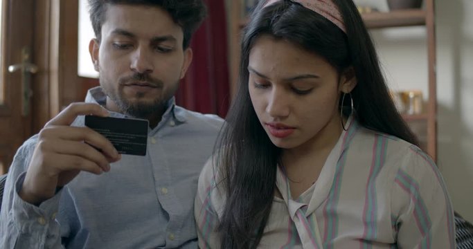 Indian couple working on a tablet as they use a credit card to pay for their luxurious lifestyle to make payments online through different cards to make their financial stability, slow-motion handheld