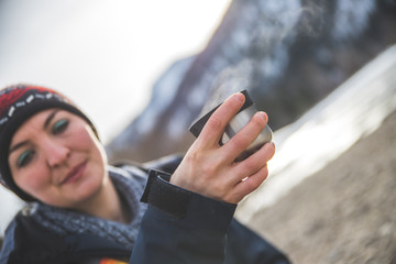 Outdoor wilderness adventure: Caucasian girl is drinking a metal cup of tea