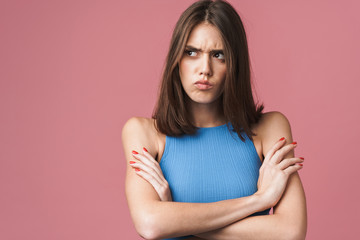 Fototapeta premium Image of angry brunette woman frowning and standing with arms crossed