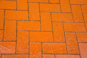 Modern paving slabs in orange, wet from rain. Background for the road. The skill of laying stone.