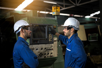 Two industrial workers operate lathes in the metalworking machinery industry. Industrial people meeting together in factory.