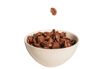 Chocolate corn flakes falling to the white bowl isolated on white. Motion.
