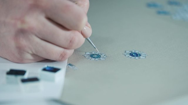 Young woman, a jewelry designer is drawing a sketch for a new ring at a jewelry production