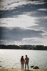 lovely couple stands by the water along river shore, holding hands together, happy family concept. love story