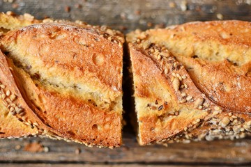 Baguette on a dark background, top view. Crispy bread with sunflower and flax seeds. Baguette cut in half.