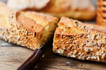 Baguette on a dark background, top view. Crispy bread with sunflower and flax seeds. Baguette cut in half.