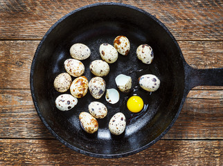quail eggs in a cast-iron pan on an old wooden table, retro style