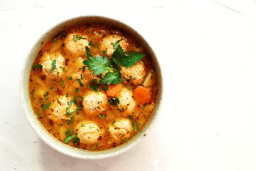 Soup with meatballs and vegetables on a white table background, top view. Vegetable soup with chicken and beans.