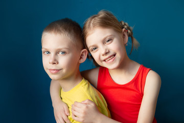 cute children brother and sister in bright clothes on a blue background